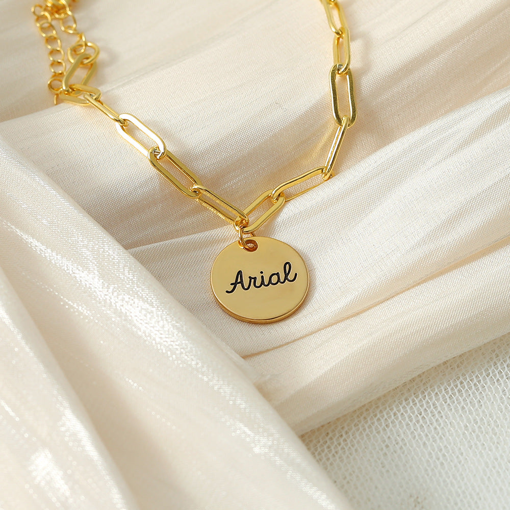 A gold-coloured bracelet with a round disc charm personalised with the name 'Arial'.