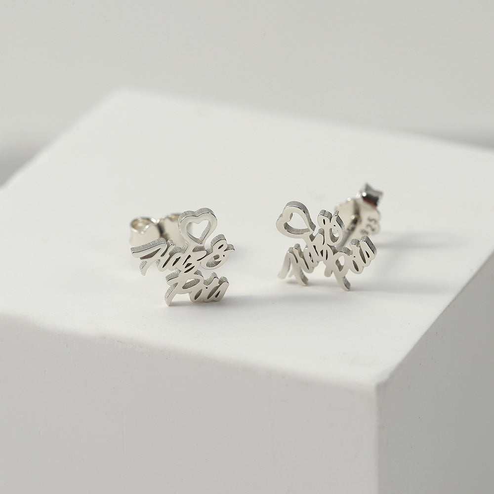 A pair of silver heart-shaped earrings with customisable name design displayed on a white platform.