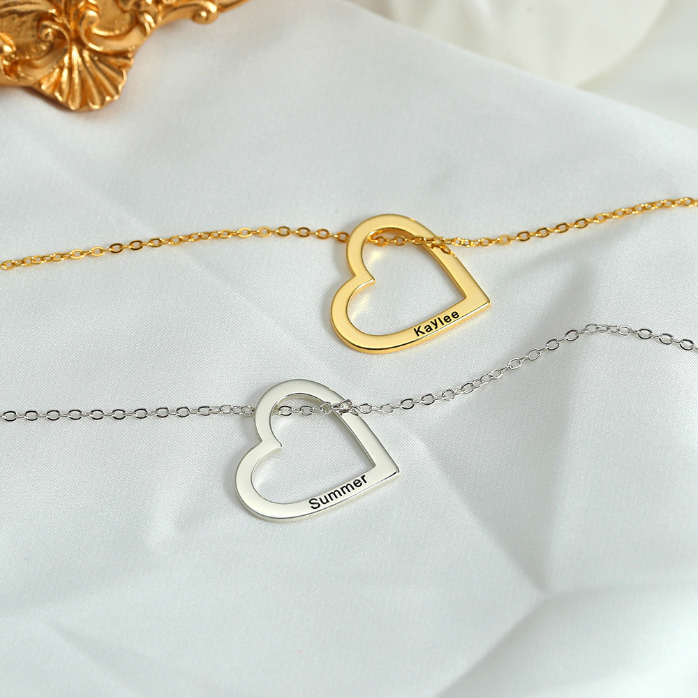 Two necklaces, one with a gold heart and the other with a silver heart, each customised with different names, lying on a white surface with a golden ornament in the background.