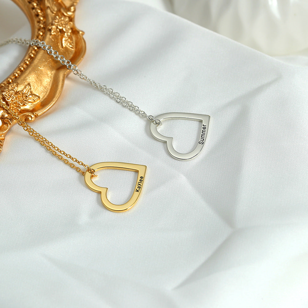 Two necklaces, one with a gold heart and the other with a silver heart, each customised with different names, lying on a white surface with a golden ornament in the background.
