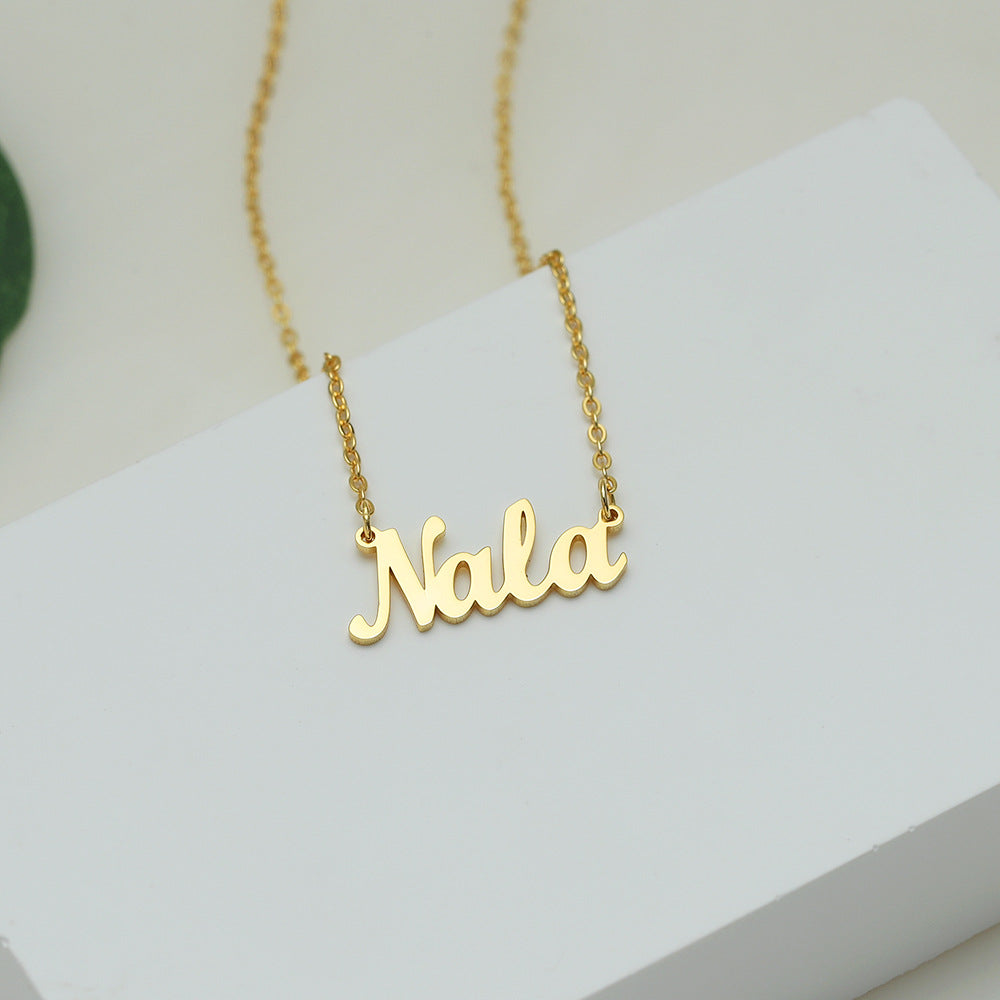 A gold-coloured name necklace with the name 'Nala' written in cursive script on a white surface.