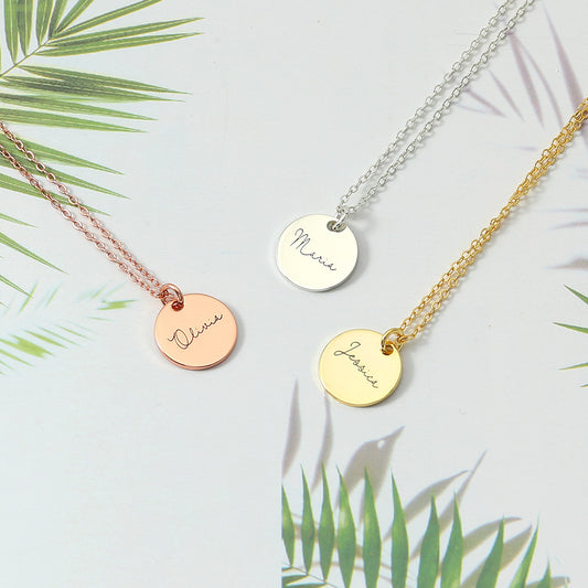Three disc necklace pendants in rose gold, silver, and gold colours, displayed on a white background with palm leaves in the background.