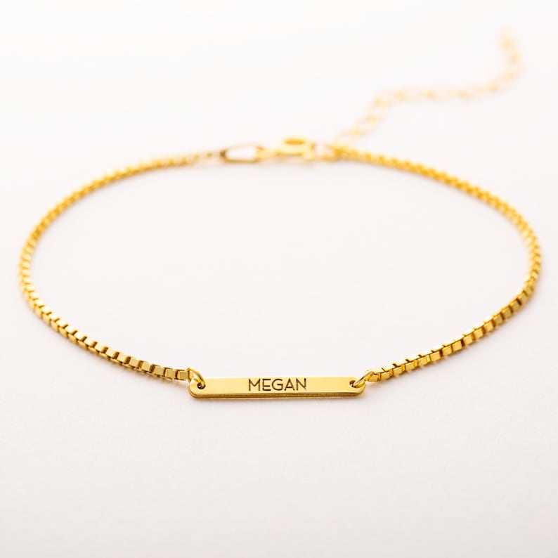 Gold bracelet with a nameplate on a white background