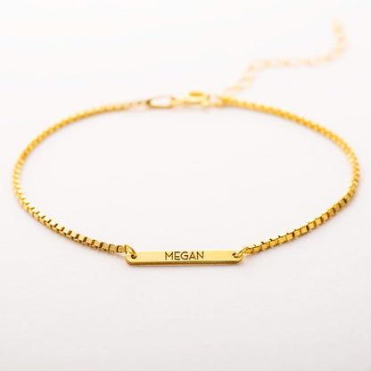 Gold bracelet with a nameplate on a white background