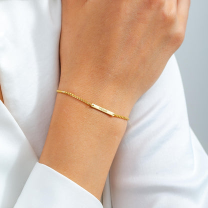 Gold bracelet with 'Megan' nameplate on a wrist with a plain background