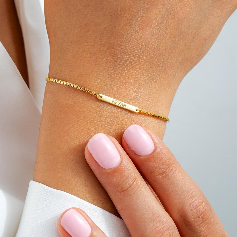 Gold bracelet with 'Megan' nameplate on a wrist with a plain background