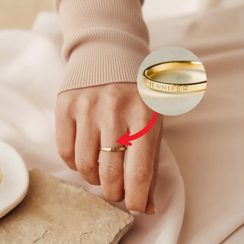 Gold ring on woman's finger with cream background