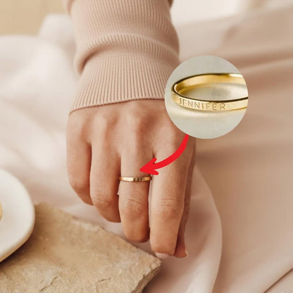 Gold ring on woman's finger with cream background