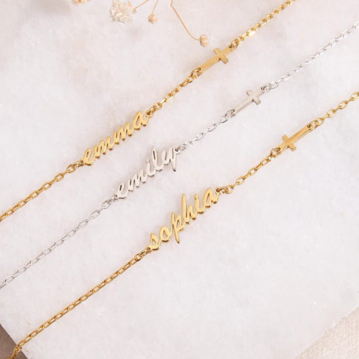 Three gold name bracelets on a white surface