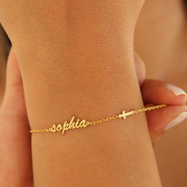 Gold bracelet with 'sophia' on a wrist against a neutral background