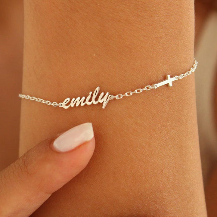 Silver bracelet with 'emily' on a wrist against a neutral background