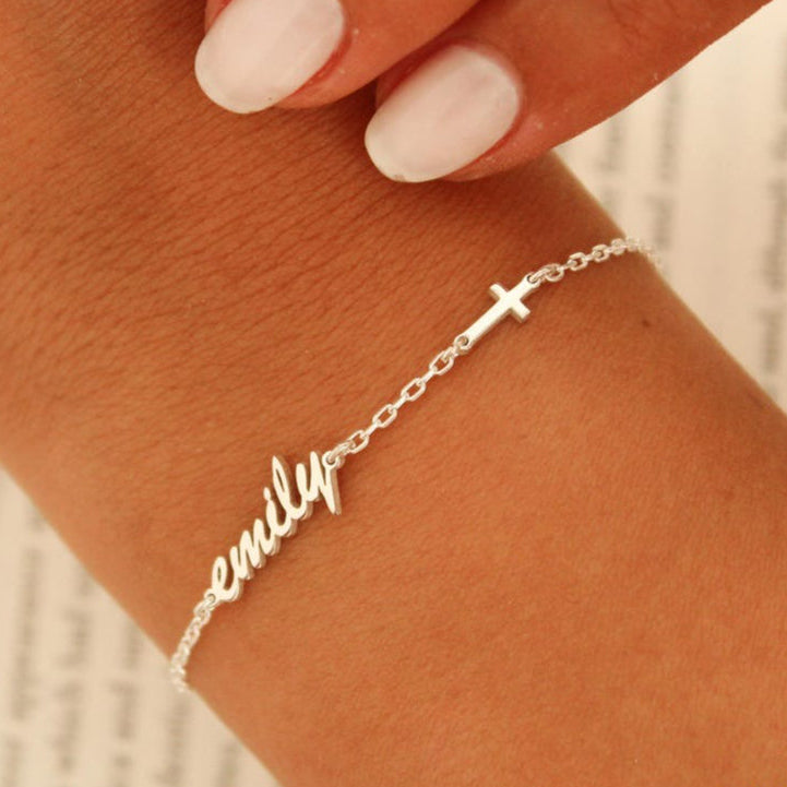 Silver bracelet with 'emily' on a wrist against a neutral background