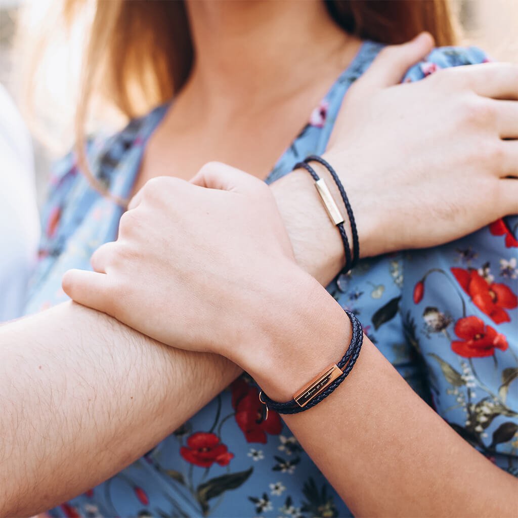 People wearing black leather wrap bracelets with a stainless steel tag, with the tag displaying an engraving.