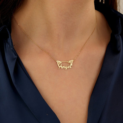 Gold necklace with 'Angel' cat pendant on a person wearing a dark blue top.