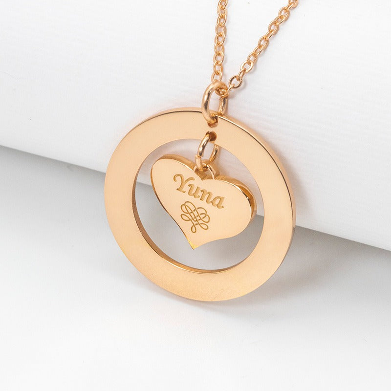 A rose gold necklace with a hollow round pendant containing a suspended love heart and a customisable name design, displayed against a white background.