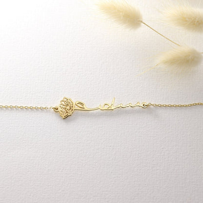 Gold bracelet with a name and flower on a light background