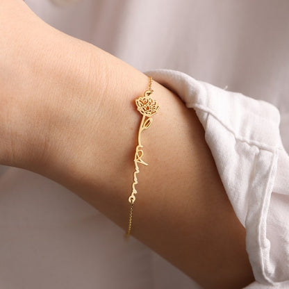 Gold bracelet with a name and flower on a wrist with a blurred background