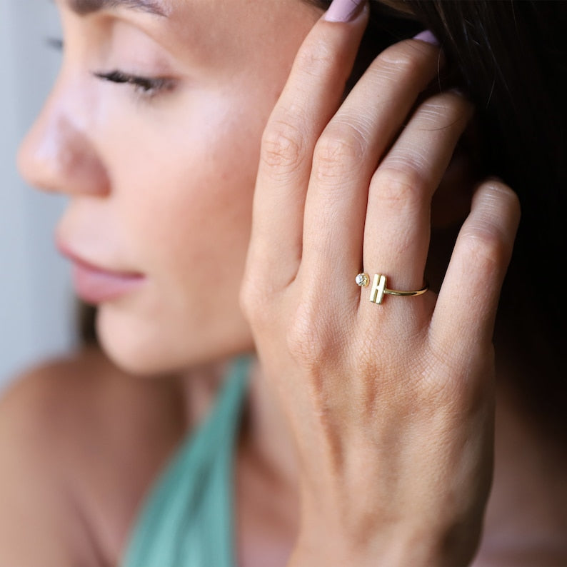 Close-up of a woman's hand with a gold initial and stone ring on her finger.