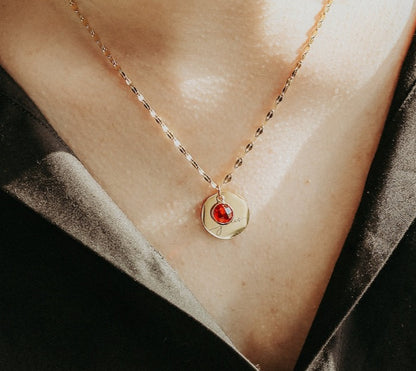 Necklace with a red gemstone pendant on a person's neck against a black background
