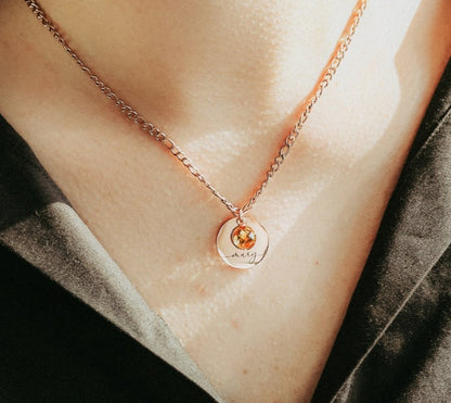 Rose gold necklace with a round pendant on a person's neck