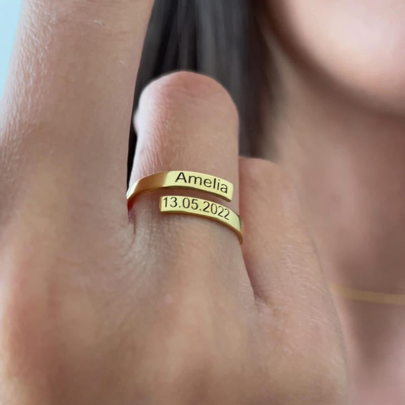 Gold ring with engraved name and date on a finger