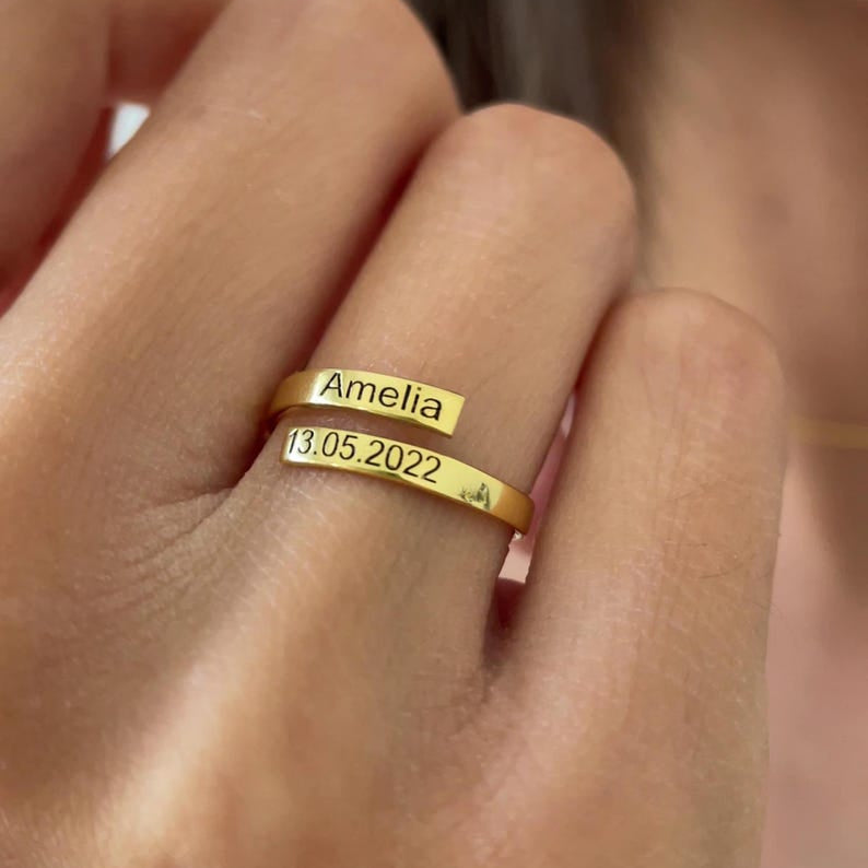 Gold ring with 'Amelia' and a date on a person's finger