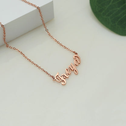 A rose gold-coloured name necklace with the name 'Freya' written in cursive script on a white surface.