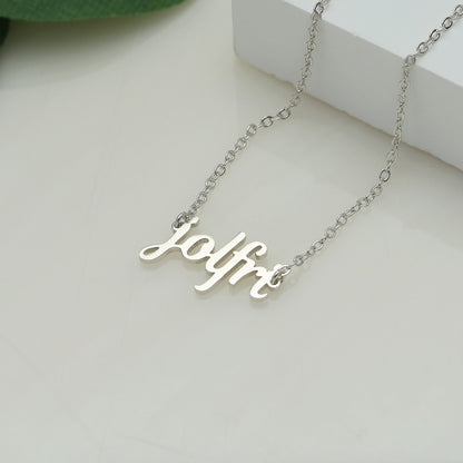 A silver-coloured name necklace with the name 'Jolfre' written in cursive script on a white surface.