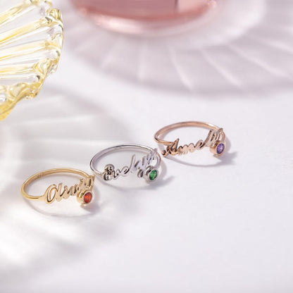 Three rings with engraved names and gemstones on a white background