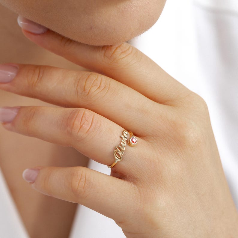 Gold ring with a small gemstone on a hand against a white background