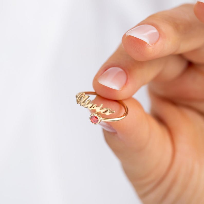 Gold ring with a red gemstone on a hand against a white background