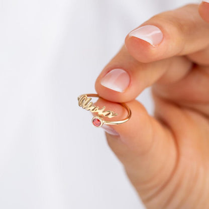 Gold ring with a red gemstone on a hand against a white background