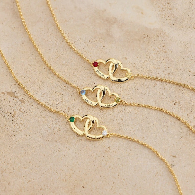 Gold heart-shaped bracelet with embedded gemstones on a beige surface