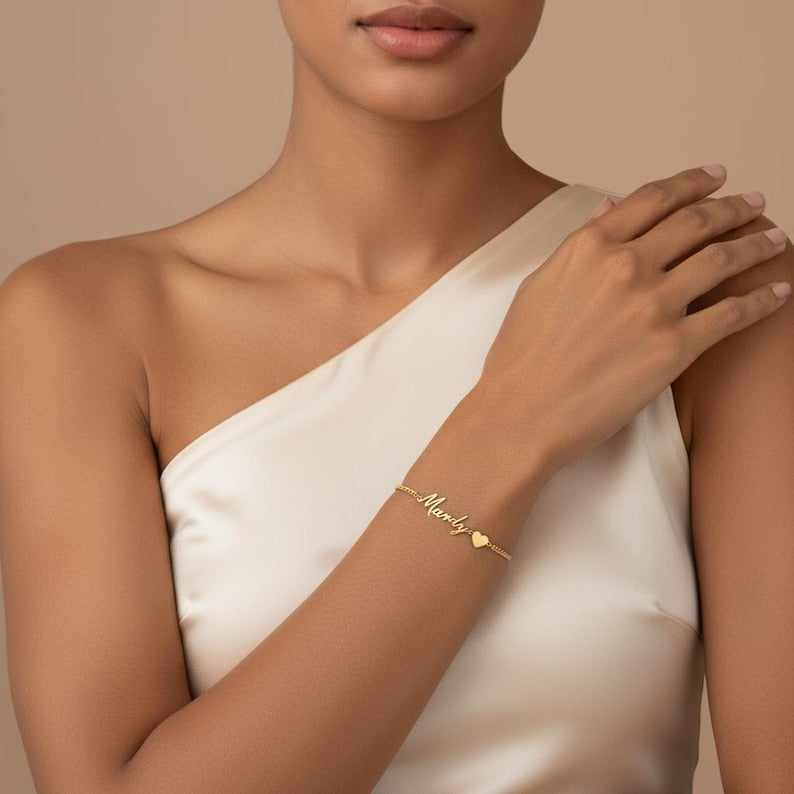 Woman wearing a gold bracelet with a heart charm on a beige background