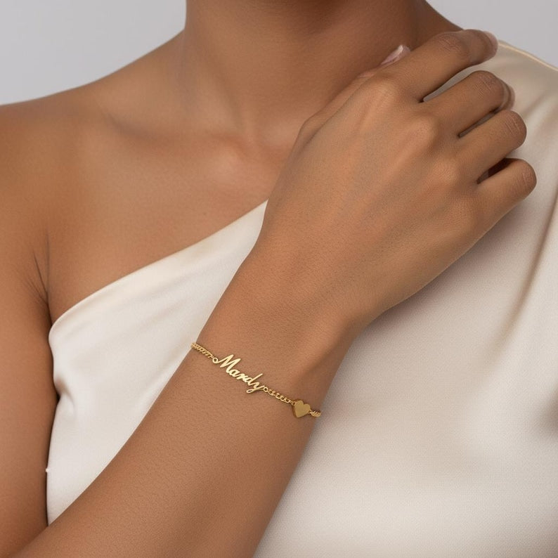 Gold bracelet with 'Mandy' on a person's wrist against a neutral background