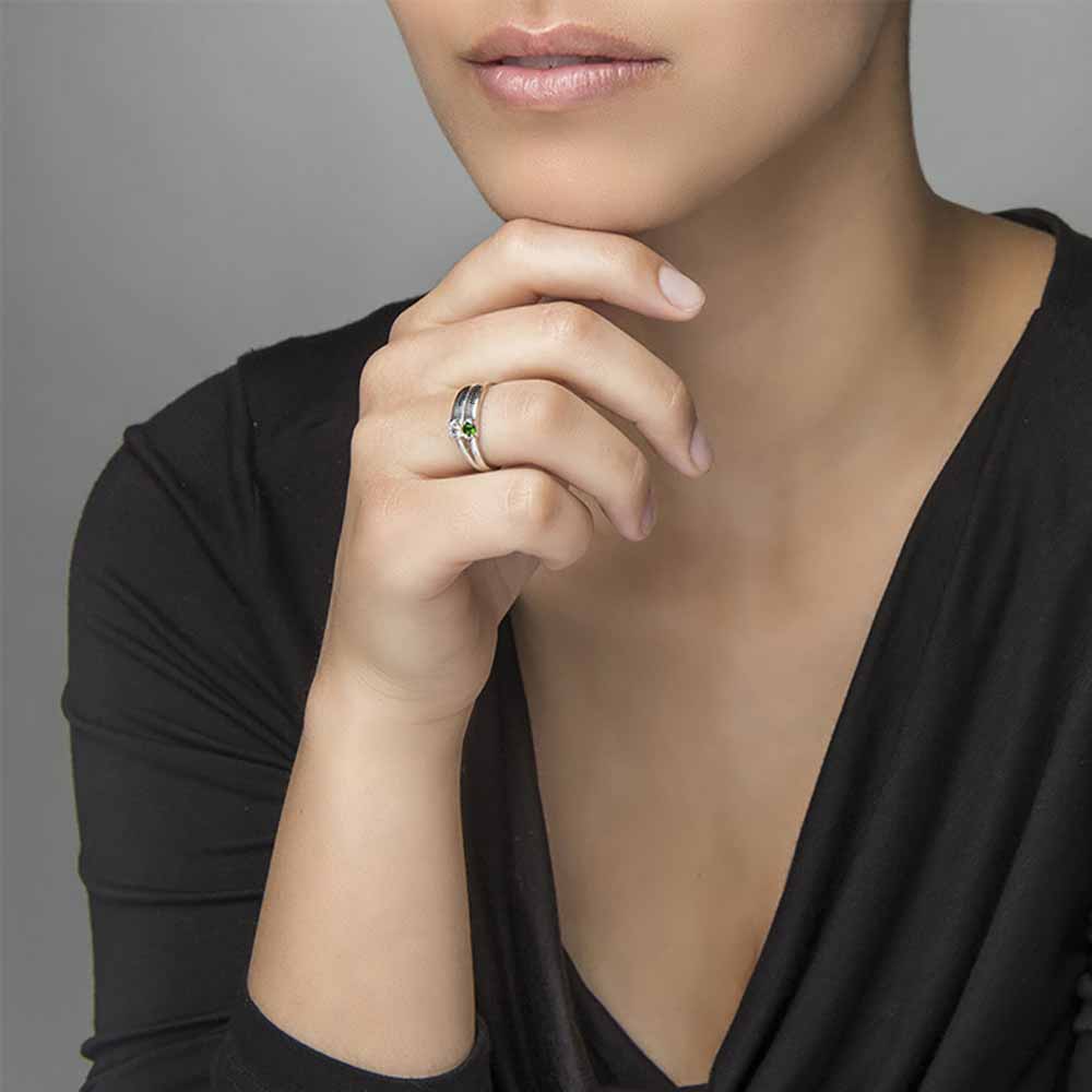 A silver-coloured ring featuring two engraved names and two gemstones.