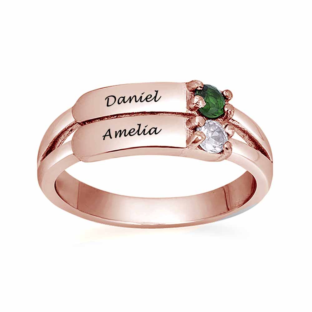 A rose gold-coloured silver ring featuring two engraved names and two gemstones.